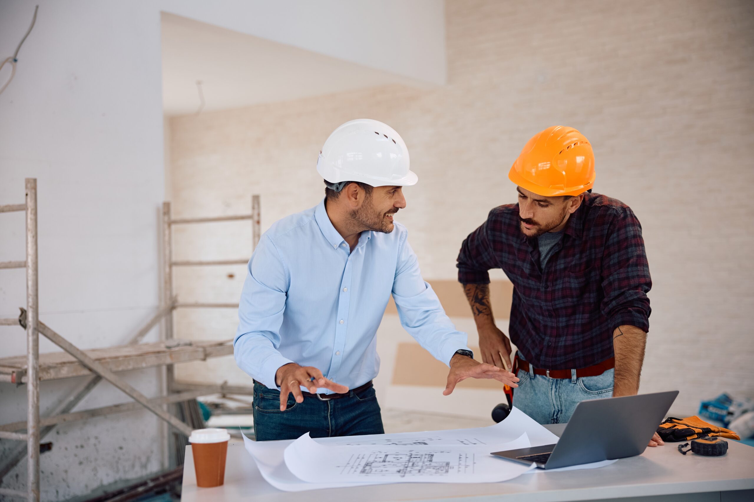 Happy,Architect,Talking,To,Construction,Worker,While,Analyzing,Blueprints,During
